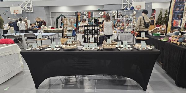 Craft fair display with jewelry and handmade items on a black-covered table.