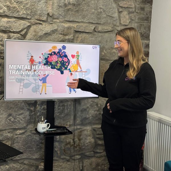 Woman presenting mental health training course on screen.