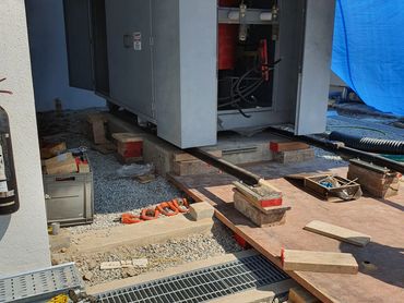 Industrial electrical equipment being installed with wooden supports and tools nearby.
