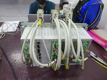 Industrial control system with cables and a person working on a laptop.