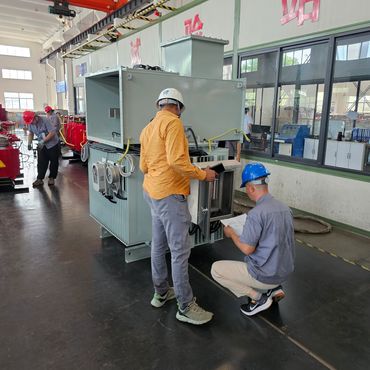 Workers inspecting and assembling electrical transformer equipment in an industrial facility.