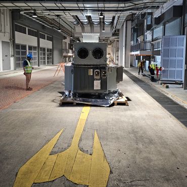 Workers in safety gear in an industrial facility with large equipment.