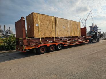 Large wooden crates secured on a red flatbed truck at an industrial site.
