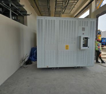 Technician inspecting a large electrical cabinet in a construction area.