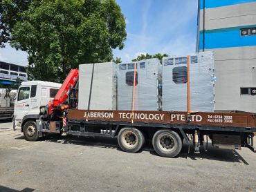 A truck loaded with wrapped industrial equipment under a clear sky.