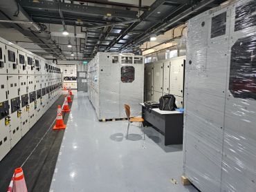 Industrial electrical control room with wrapped equipment and safety cones.