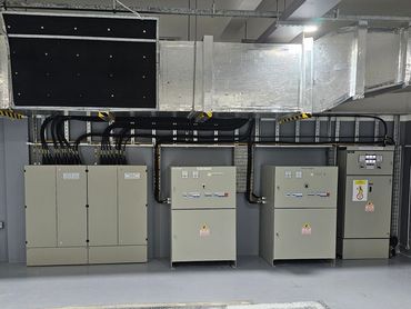 Industrial electrical control panels with ventilation ducts above in a clean room.