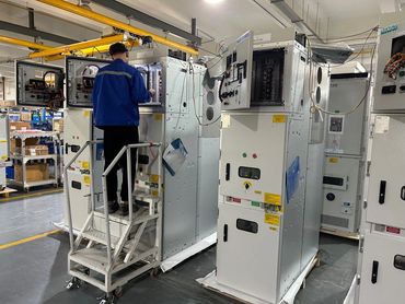 Technician working on electrical switchgear in an industrial facility.