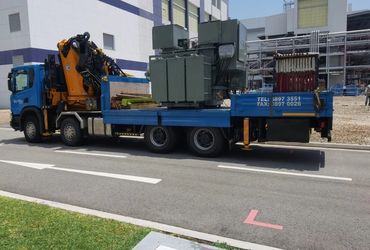 Blue truck carrying large electrical transformers and equipment.