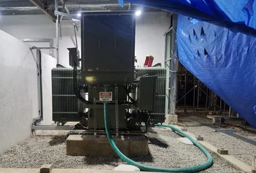 Industrial electrical transformer with warning sign and protective covering.