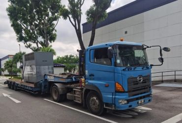Blue flatbed truck parked with industrial equipment on the trailer.