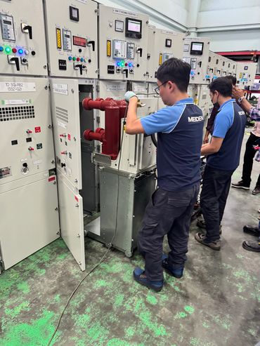 Technicians working on electrical control panels in an industrial setting.