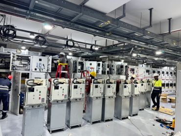 Technicians working on electrical panels in an industrial setting.