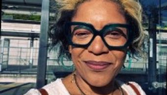 Woman with glasses outdoors smiling.
