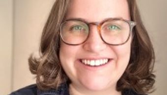 Smiling woman with glasses and curly hair.