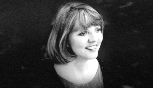 Black and white portrait of a smiling woman with short hair.