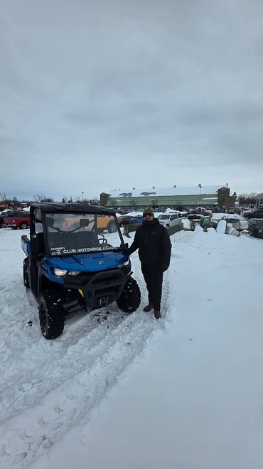 La scène se déroule à l'extérieur, sur un terrain enneigé, en arrière-plan sous un ciel hivernal.
