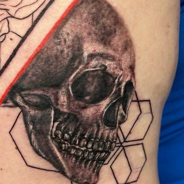 Realistic black and grey skull tattoo with geometric details