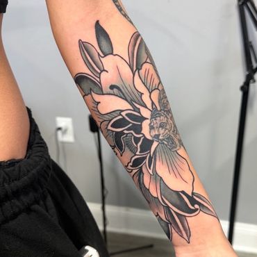 Black and grey floral forearm tattoo with bold shading