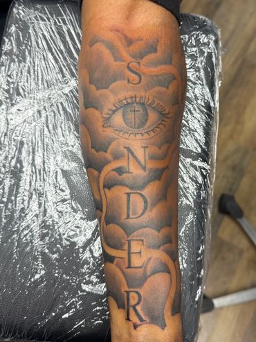 Black and grey eye, clouds and lettering forearm