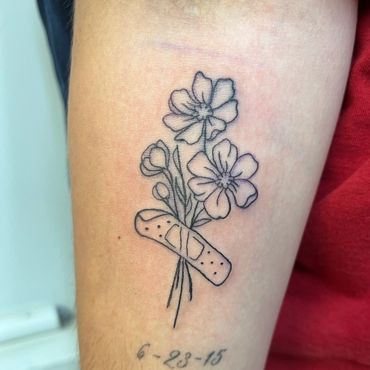 Fine line flowers wrapped in a bandage tattoo by Eva