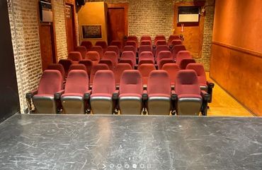 View from stage showing empty red theater seats in a small room.