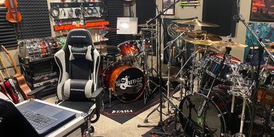 A well-equipped music studio with drums, guitars, and recording gear.