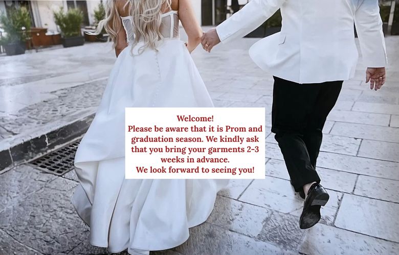 A groom lifts and kisses his bride in a sunlit rustic street.