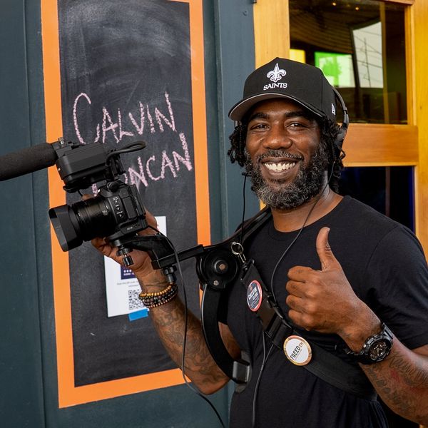 Smiling man with camera giving a thumbs up.