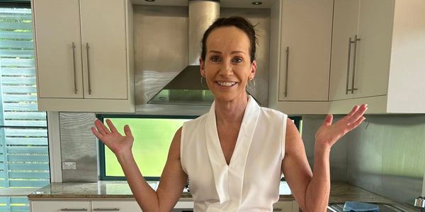 Brianne Tillyer is on a bench hands open with a smile. She expresses joy in helping people with comm