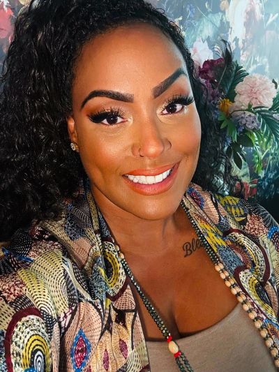 Smiling woman with curly hair and colorful patterned top.