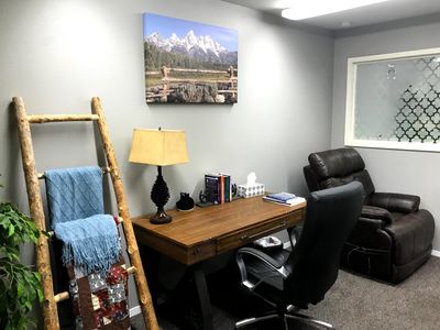 Cozy office corner with wooden desk and leather chairs.