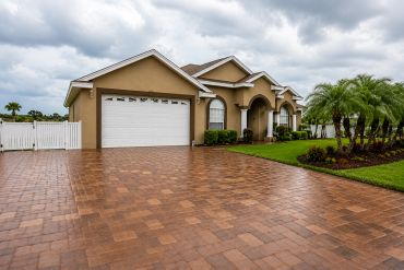 Finished paver driveway leading to a landscaped residential property.