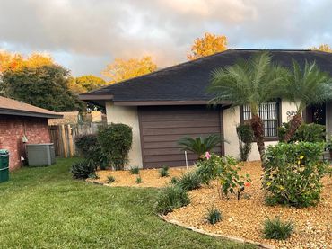 Residential front yard with trimmed shrubs, decorative rock, and refreshed landscaping.