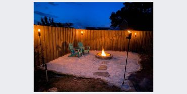 Former lawn transformed into a rock seating area with a fire pit and outdoor chairs.