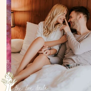 Happy young couple cuddles affectionately in bed with white linens.