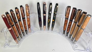 Collection of handcrafted wooden pens on a clear stand.