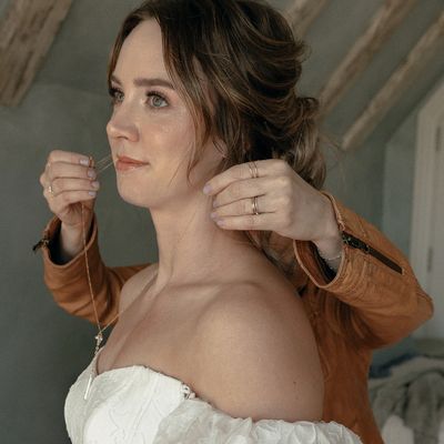 Bride getting a necklace put on by someone.