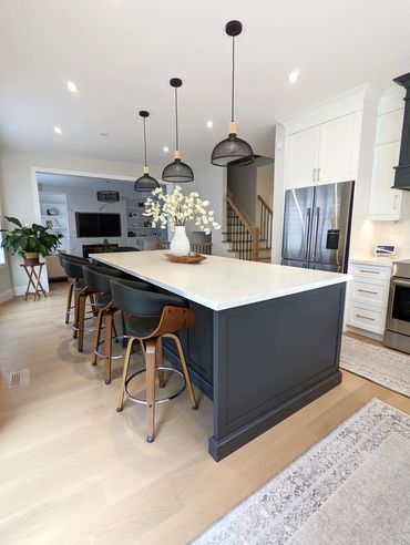 Modern kitchen with a large island, pendant lights, and wooden bar stools.