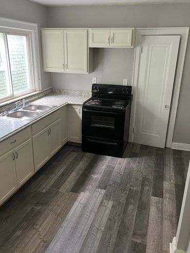 Kitchen after wall removal, flooring, cabinet install, and painting.