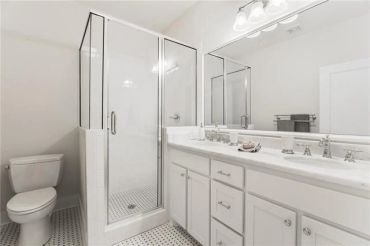 Clean white bathroom with mosaic tile floor and Carrera marble counter tops
