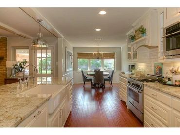Remodeled kitchen with custom cabinetry, granite countertops, apron front sink, & hardwood floors