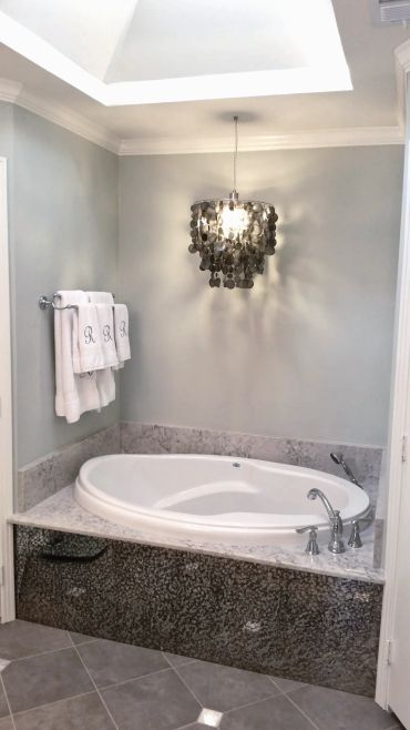 Large soaker tub with marble top. Glass tile face and chandelier.