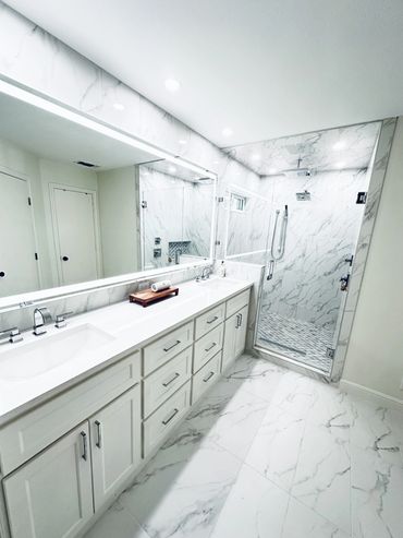 Contemporary Bathroom: White cabinets, marble top, marble tile, walk-in shower, & large light mirror