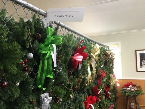A display of custom holiday wreaths decorated with bows and ornaments.