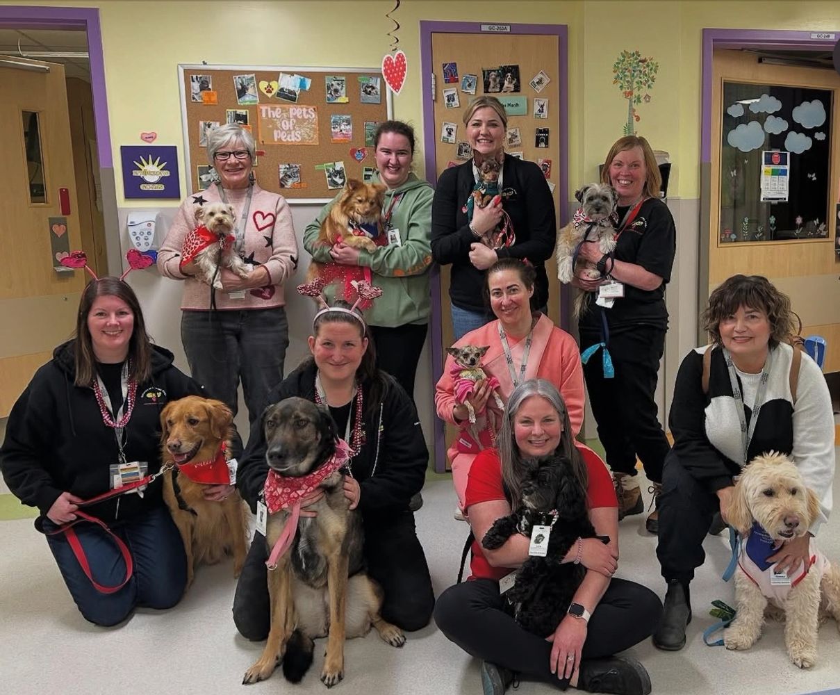 Group photo of people with their dogs in a decorated room.