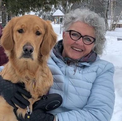 Woman in winter coat hugging a golden retriever in snowy park.