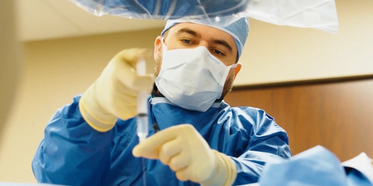 Doctor preparing a syringe in surgical attire.