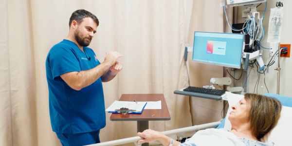 Nurse explains medication to patient in hospital bed.