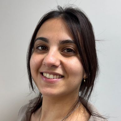 Smiling woman with long dark hair against a plain background.